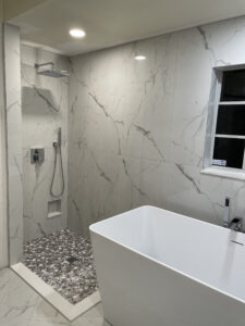 Modern bathroom design with marble tile shower, pebble floor, and freestanding tub, creating a spa-like home retreat.