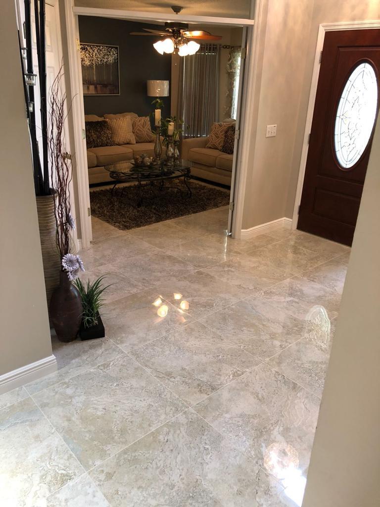 Elegant home interior with marble tile flooring, living room view, and dark wood front door. Home decor with vases and plants.