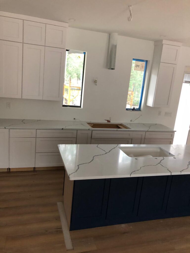 New kitchen installation with white cabinets, marble countertops, and a blue kitchen island, showcasing kitchen services.